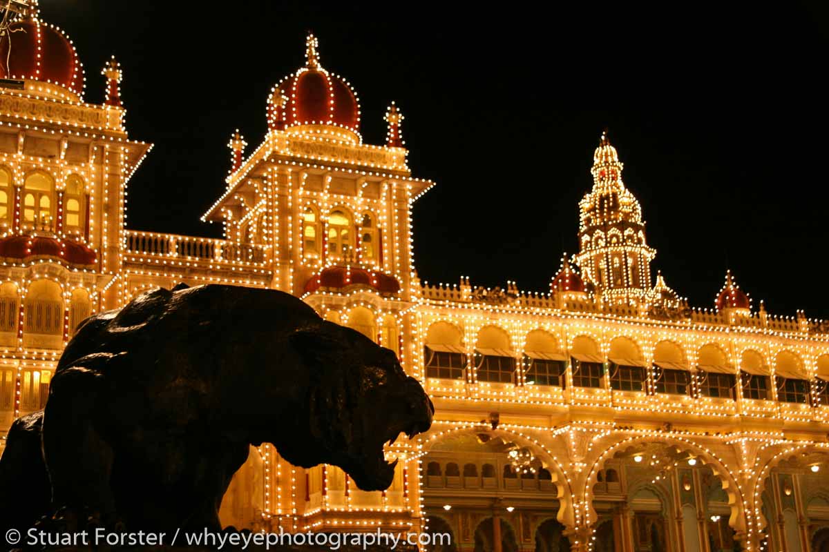 A tiger statue is silhouetted in front of illuminations at Mysore Palace, Mysore, Karnataka.